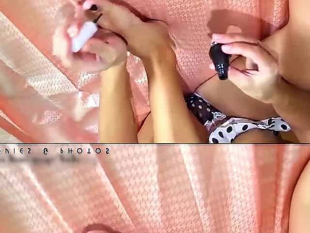 A youthful lady paints her toenails with ebony varnish. That babe's wearing ebony and white pants and a bl