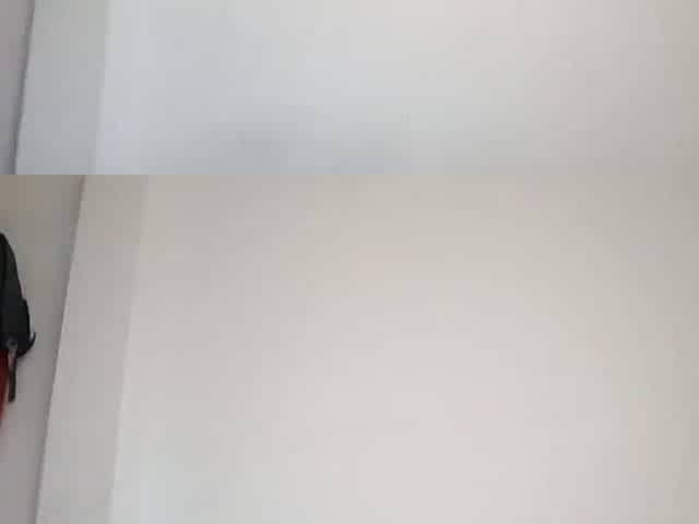 The dog lies face down, sucks and receives milk whilst the woman is in the kitchen