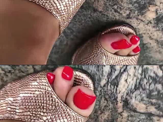 Wifes feet with red toenails crushing a kiwi fruit