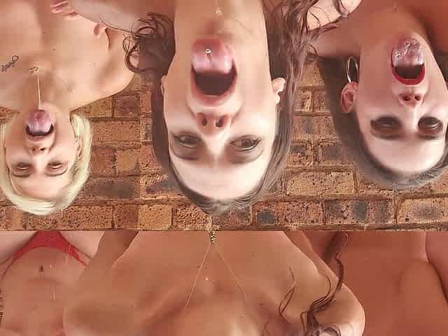 three strumpets sit outside with their tongue's out playing with spit
