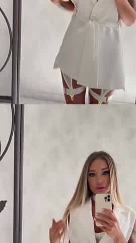 Monika Fox in White Posing in Front of a Mirror Before Shooting